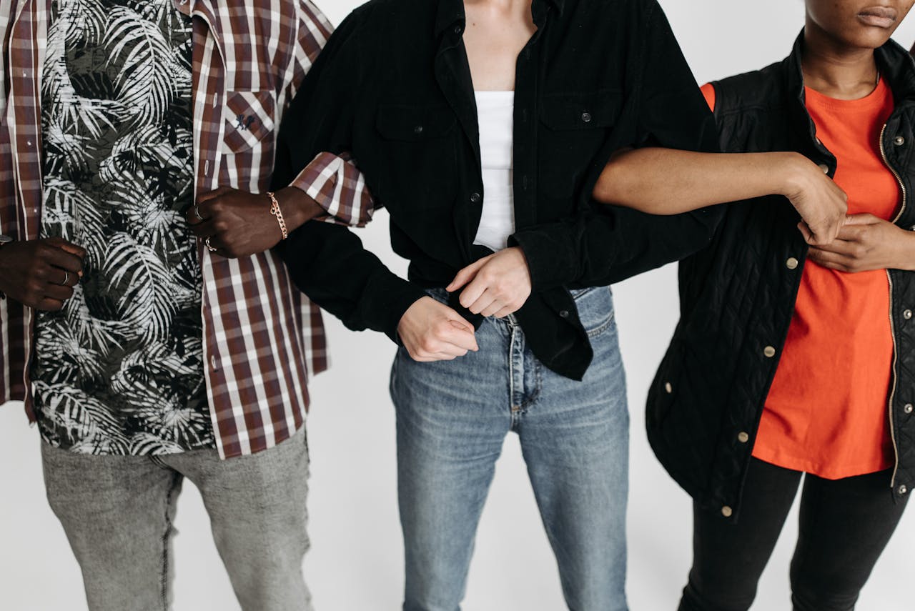 Close-up of three diverse individuals linking arms, showcasing unity and connection in a studio setting.